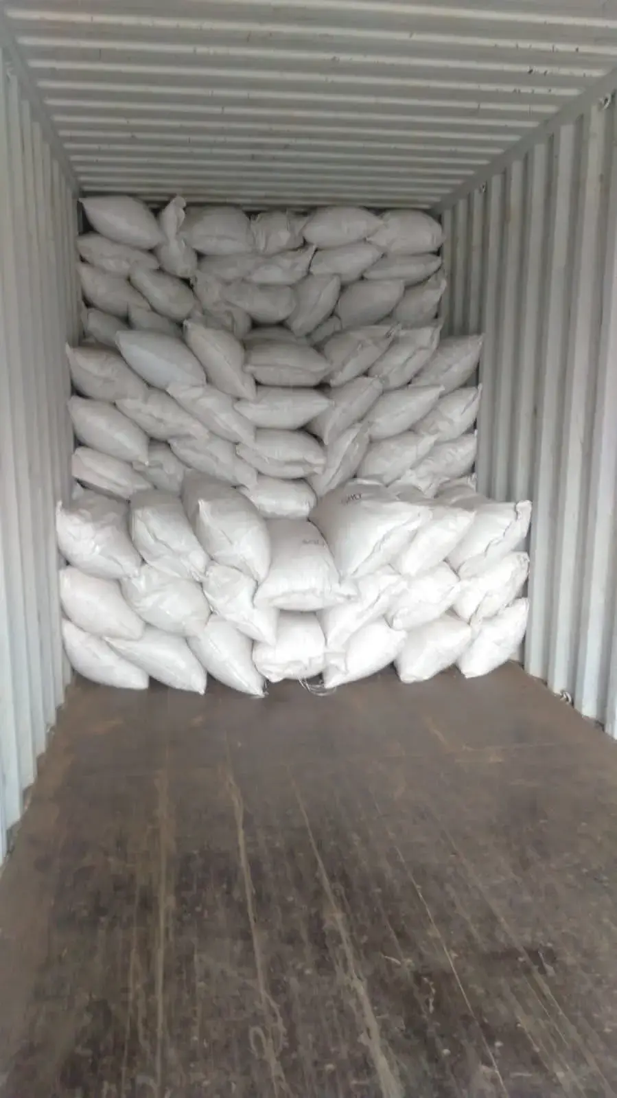 Filled sacks stacked in courses inside a container.