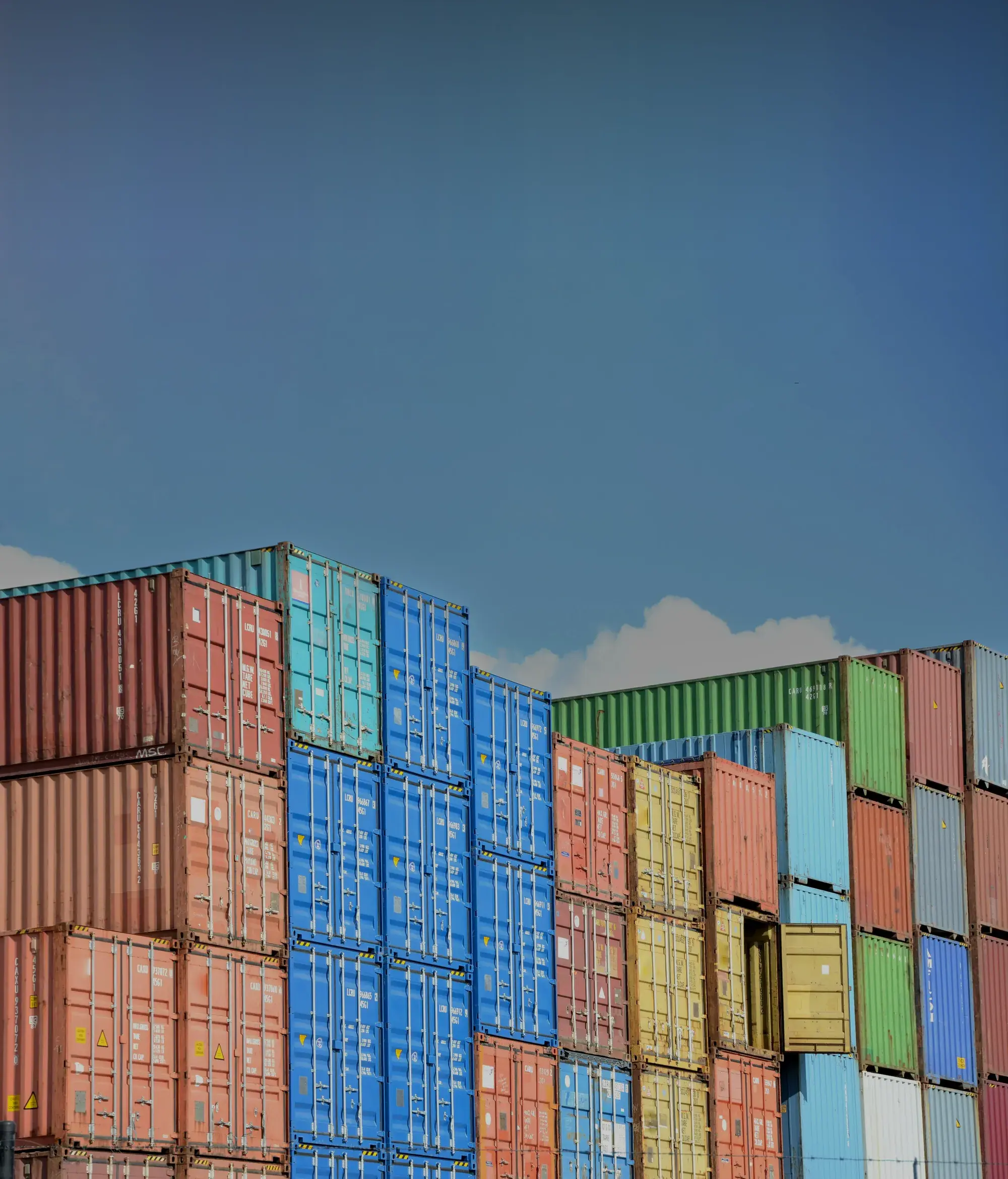 Shipping containers stacked at a port under open sky.